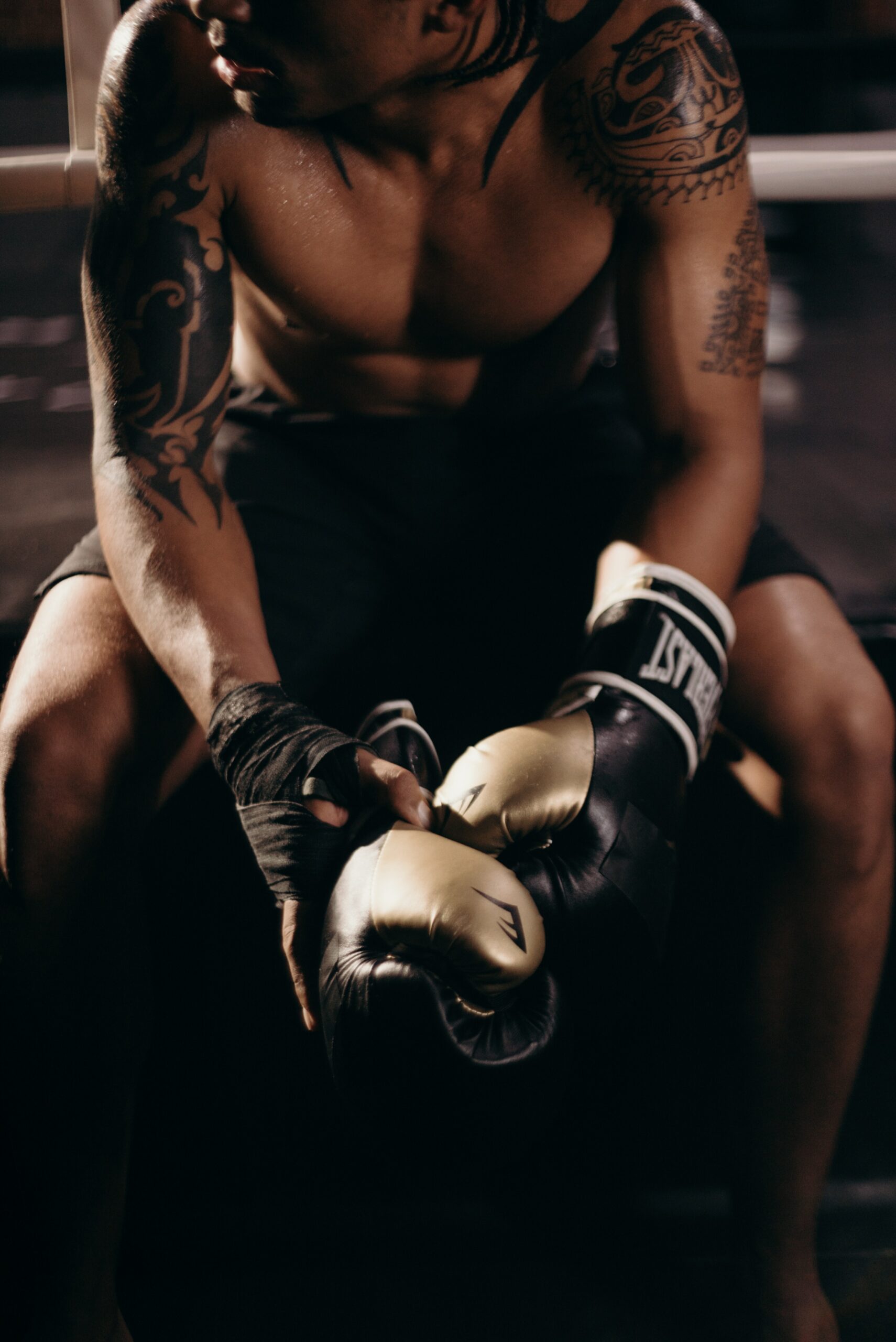 A boxer resting after a training session wearing Everlast boxing gloves